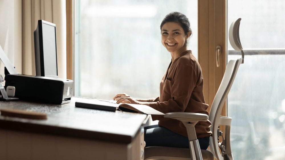 A Women is Smiling and Working on the Laptop at PEO Canada