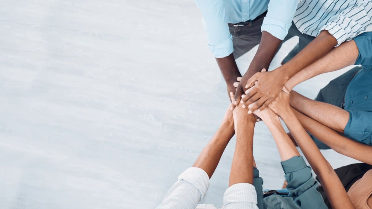 Individuals Stacking Hands to Show Teamwork and Mutual Support at PEO Canada