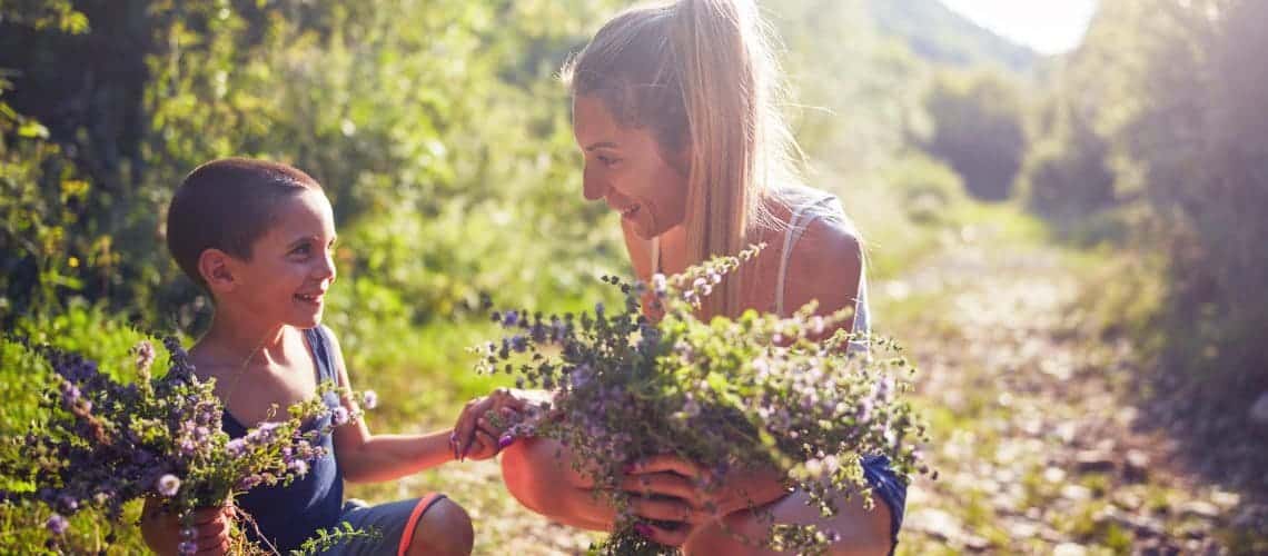 A woman gathering flowers with a kid in a garden