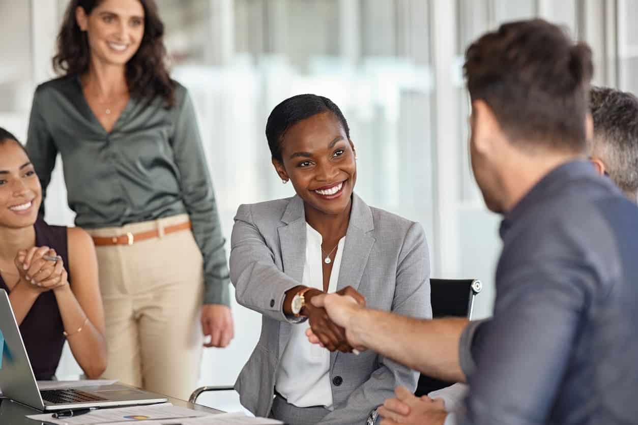 A woman shaking hands with another man during a meeting