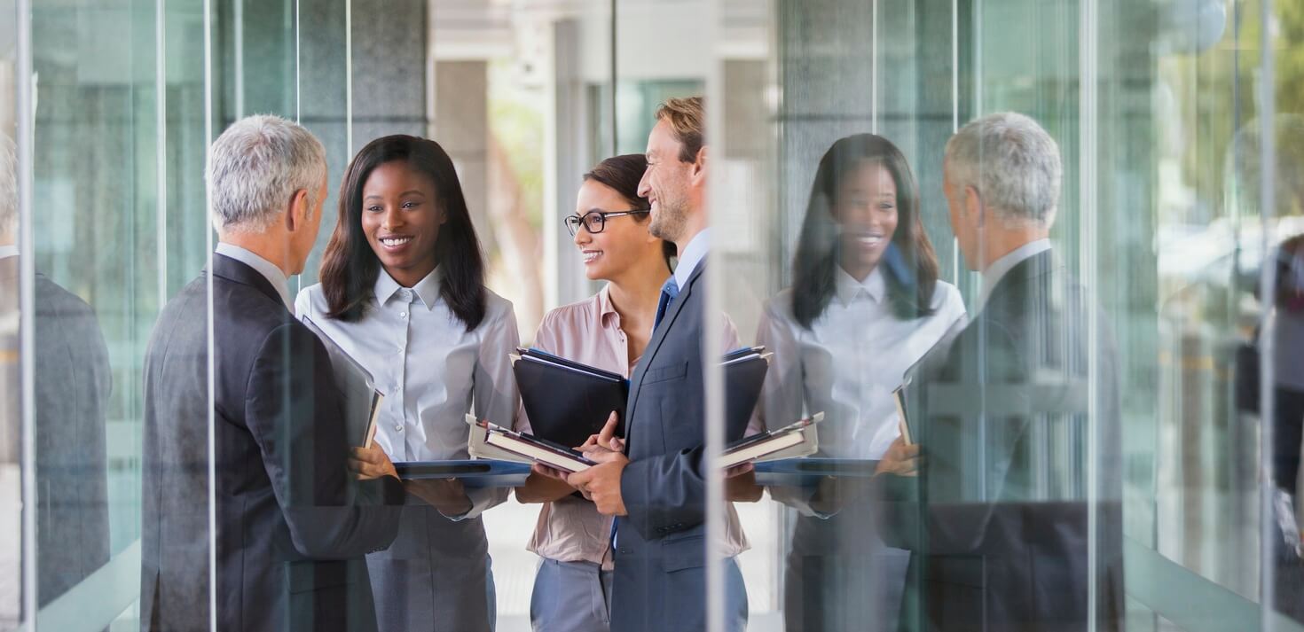 Business professionals standing and discussing in front of glass doors