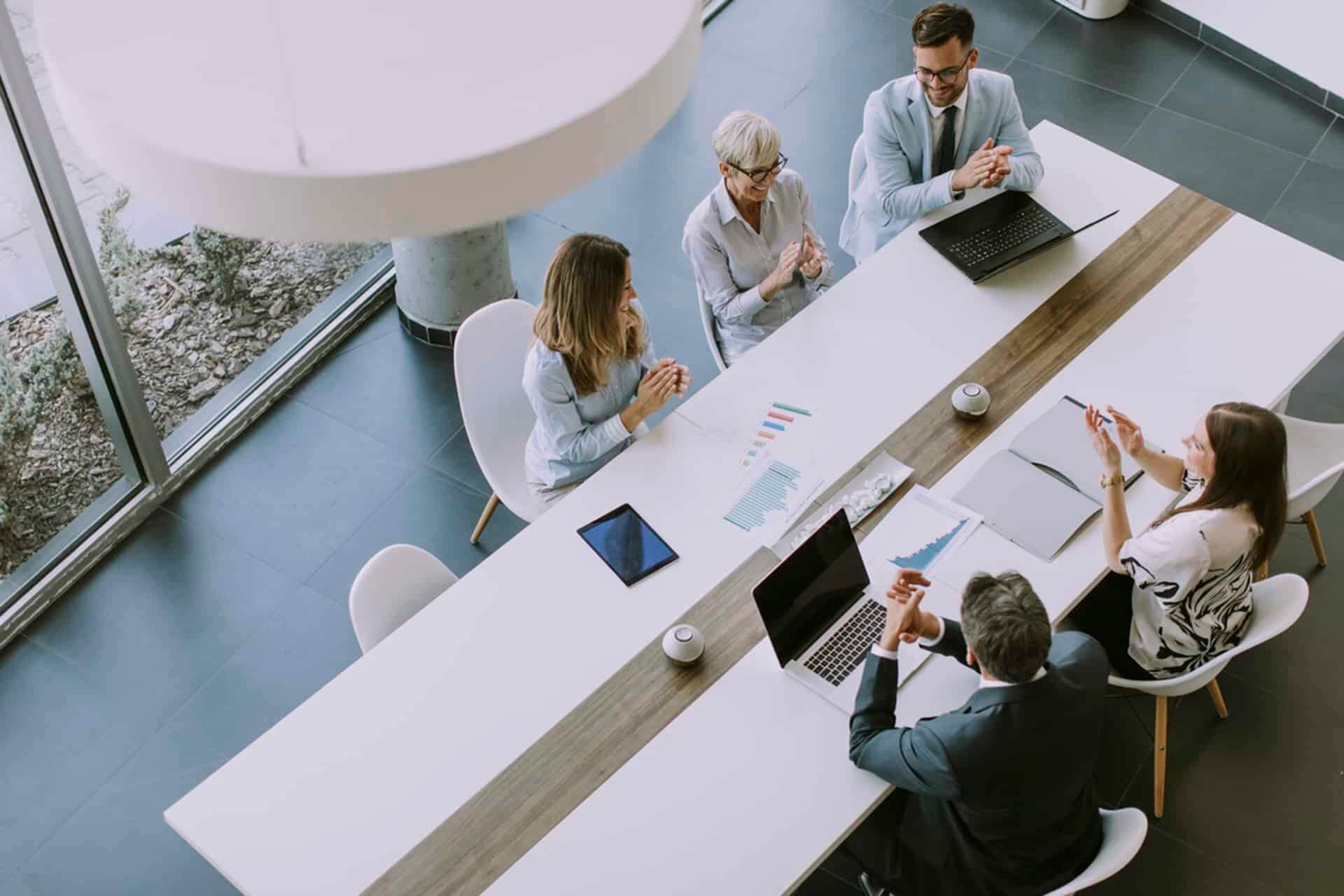 A group of professionals engaged in discussion around a conference table in an office setting