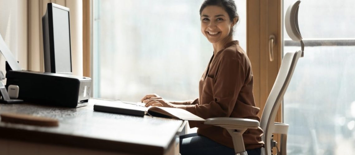 A Women is Smiling and Working on the Laptop at PEO Canada