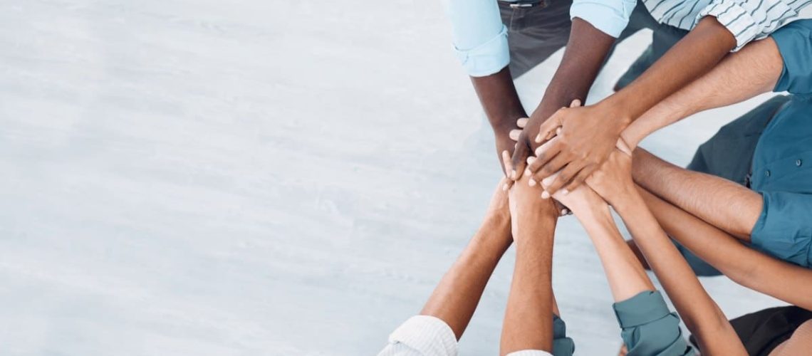 Individuals Stacking Hands to Show Teamwork and Mutual Support at PEO Canada