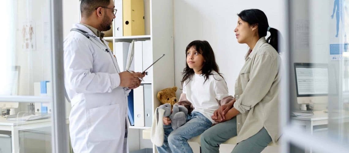 A doctor speaks with a girl and her mother providing provincial healthcare tips in North America